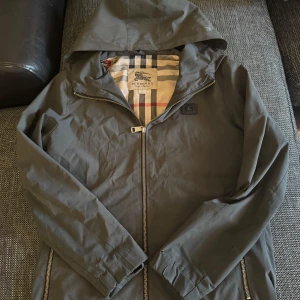 Burberry jacka  - Tjena säljer denna jätte sällsynta burberry jackan som går aldrig att hitta längre den är ganska gammal köptes i outlet i Tyskland den är i storlek S. Jackan är i grå, grön färg och har ett stort snyggt burberry märke där bak som man ser. Köptes för 500 euro som är runt 5500 kr. Skriv för fler bilder på jackan. Jag är 180 och väger 68 och den passar bra på mig skulle säga att den e lite tight på mig 