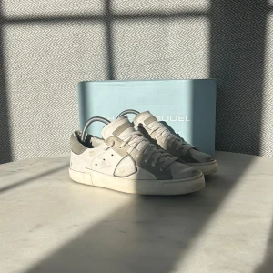 Philippe Model skor  - Snygga sneakers från Philippe Model i en stilren kombination av grått och vitt samt ljusblått. Skorna har en klassisk design med snörning och en diskret logga på sidan. Stolek: 40 men passar även 41. Skick: (7/10) Enda defekten är att hälen på insidan är lite sliten. 