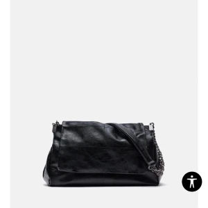 Svart axelväska med kedjedetaljer - Snygg svart axelväska i skinn med kedjedetaljer. Sparsamt använd. 