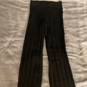 Svarta byxor från H&M - Snygga svarta ribbade byxor från H&M i en avslappnad passform. Byxorna har en hög midja och är perfekta för en stilren look. De är tillverkade i ett mjukt och stretchigt material som ger komfort hela dagen. I storlek xs,  fint skick ⭐️
