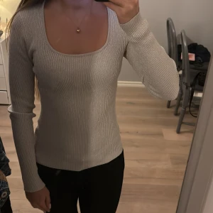 Glittrig grå/silvrig ribbad tröja - Säljer en snygg grå tröja med glittrande detaljer. Tröjan är ribbad och har en figurnära passform med långa ärmar. Perfekt för att lägga till lite glitter i vardagen!