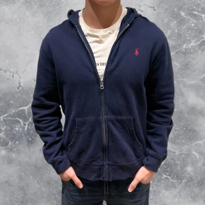 Ralph Lauren Zip Hoodie Blå - •Ralph Lauren Full-Zip Hoodie Navy Blå. Skick: 8/10, Inga skador! Storlek: XL 18-20 Ungdom = S, herr~. •Mått, axel-neråt: 60 cm, bredd: 48 cm. Modell: 173 cm, 63 kg, sitter bra på modellen! Authentic: ✅. Hör av dig vid frågor eller funderingar, mvh Hessler’s;) 