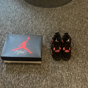 Svarta och röda Nike Air Jordans - Snygga Nike Air Jordans i svart och rött med klassisk Jumpman-logga. Skorna har snörning och en iögonfallande design med röda detaljer på sidorna och hälen. Perfekta för sneaker-entusiaster som vill sticka ut.