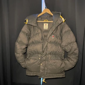 Fjällräven jacka - Grå - Säljer en grå dunjacka från Fjällräven, Expedition Series 1974. Jackan är använd bara ett fåtal gånger och är i helt nyskick ser dock lite skrynklig ut just nu men de är för att den legat i min garderob ett tag men de är bara att puffa till den. Nypris på denna ligger mellan 7-8 tusen men priset går att diskutera vid snabb affär.