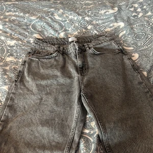 Grå jeansbyxor från Grunt - Snygga grå jeansbyxor från Grunt med en klassisk straight passform. De har en midwaist design och är perfekta för en avslappnad stil. Byxorna har både knappar och dragkedja framtill.
