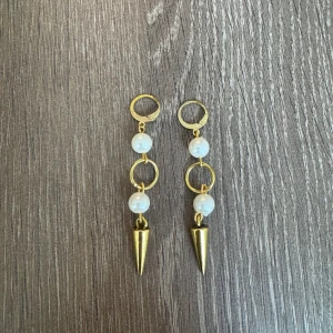 Guldplaterade örhängen med pärlor  - Eleganta guldörhängen med två vita pärlor och konformade hängen. Perfekta för att ge en stilfull touch till din outfit.