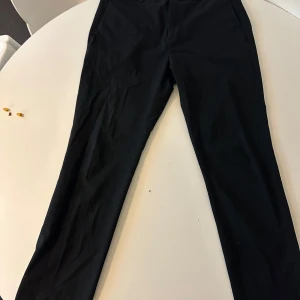 Svarta kostymbyxor - Eleganta svarta kostymbyxor från HM med en stilren design. Perfekta för en formell look eller en uppklädd vardag. Byxorna har en rak passform och är tillverkade i ett bekvämt material.