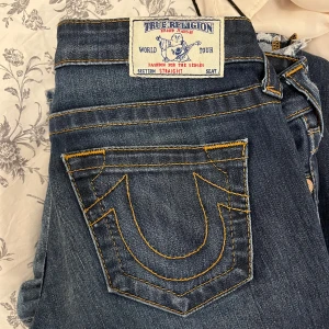 Lågmidjade jeans från True Religion - Snygga blå jeans från True Religion Jeansen har en straight passform och låg midja och är köpta vintage i Spanien. De är lite långa på mig som är 168 cm lång W27 💕