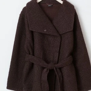 Brun kappa från Gina Tricot - Säljer min bruna kappa i boucle material från Gina tricot. Har knytning i midjan men man kan ha den öppen också. Aldrig använd med prislapp kvar. Lite oversize i storleken men det är bara snyggt. 