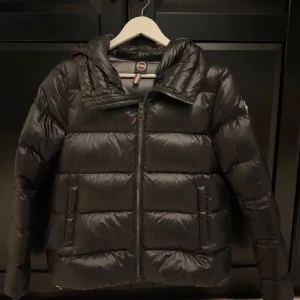 Svart pufferjacka från Colmar - Säljer min helt oanndvända dunjacka från colmar. Jackan är köpt på jhonells för 6000, pris kan diskuteras. Jackan är i storlek 40 men skulle säga att den sitter mer som en 36 då den är liten i storleken. Perfekt för kalla vinterdagar och höstkvällar 