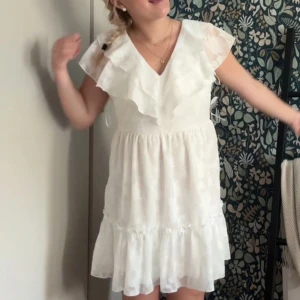 Vit student klänning - Så söt klänning. Den har en kort längd och är perfekt för studenten😍 Den är ärmlös med en luftig passform och har en vacker volang runt axlarna. 