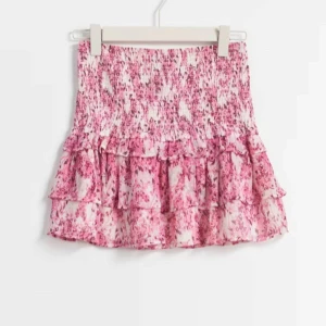 Rosa blommig kjol med volang - En kjol från Gina Tricot som inte har kommit till användning. Köpte den innan sommaren och använt den runt 2 gånger. Köpte den för mer än 300. Den elastiska midjan ger en bekväm passform.