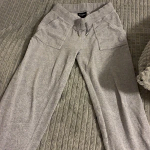  Juicy byxor - Säljer ett par grå mjukisbyxor från Juicy Couture med snörning i midjan och praktiska fickor med knappar. Storlek S men Om man är storlek M går det oxå att använda.