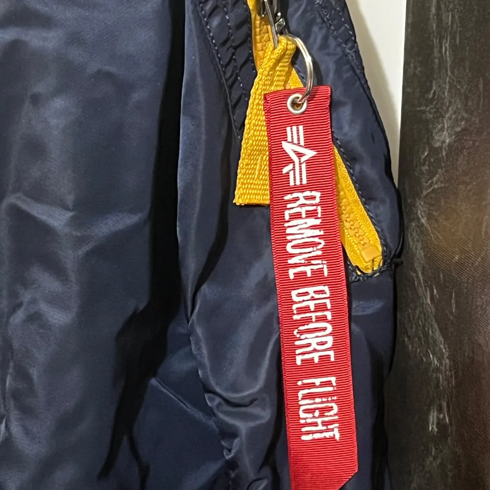 Säljer en snygg mörkblå bomberjacka från Alpha Industries i storlek medium. Jackan har en cool gul insida och flera dragkedjor. Den har också en ikonisk 'Remove Before Flight'-tag. Perfekt för höst, vår och sommar.. Takit.