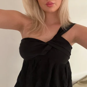 Svart oneshoulder topp - Snygg svart oneshoulder topp med en twistdetalj framtill.  Knappt använd! 