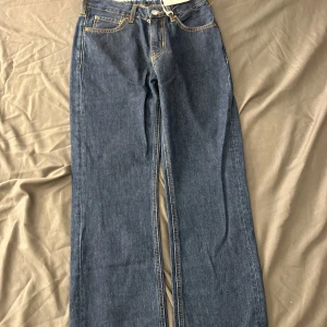 Blå jeans med rak passform - Snygga blå jeans med rak passform och låg midja. Klassisk design med fem fickor och kontrasterande sömmar. Perfekta för en avslappnad stil.