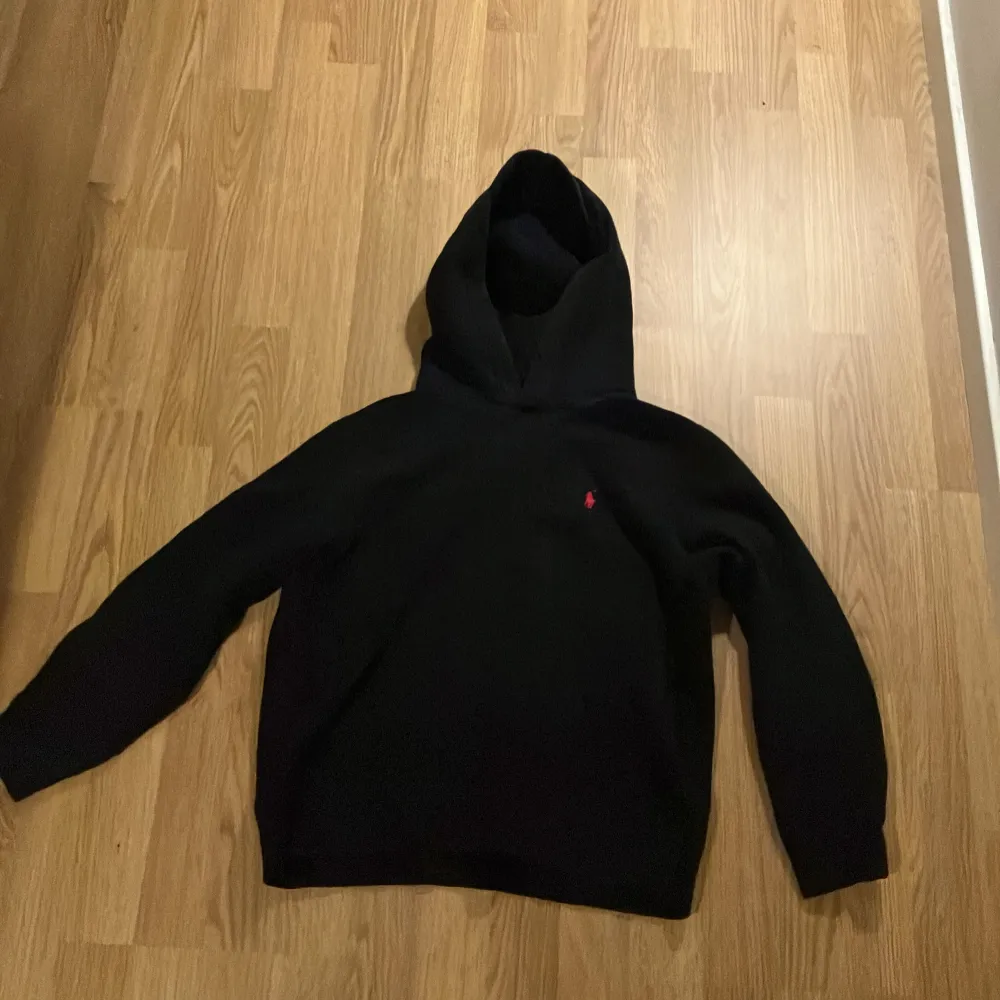 Säljer en stilren svart hoodie från Polo Ralph Lauren i storlek 160 barn Den har en klassisk design med en liten röd logga på bröstet. Perfekt för både vardag och chill. Grymt skön och passar till allt! 🖤. Tröjor & Koftor.