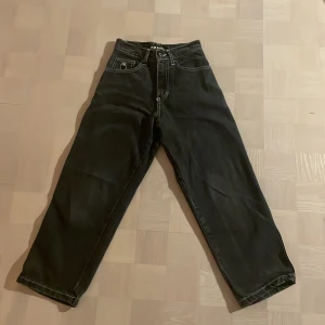 Svarta jeans från Bigfoot - Säljer ett par svarta jeans från Bigfoot i bra skick. De har en loose passform och är högmidjade, vilket ger en skön och avslappnad stil. Perfekta för höst och vinter med sin robusta design. Detaljer som broderad logga på fickan ger dem en unik touch.