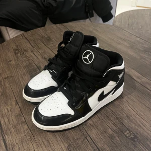 Svartvita Nike Air Jordans - Säljer ett par snygga svartvita Nike Air Jordans i mycket bra skick. Skorna har en klassisk design med svart snörning och den ikoniska Air Jordan-loggan på sidan. Perfekta för både vardag och fest!