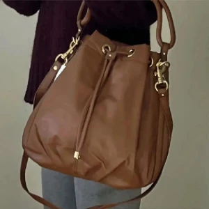 Brun väska  - Säljer en snygg brun väska. Väskan har en praktisk dragsko och guldfärgade detaljer som ger den en elegant touch. Perfekt för både vardag och fest! Helt ny. Använd gärna KÖP NU om du vill köpa.