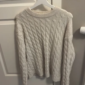 Beige stickad tröja - Mysig vit stickad tröja med kabelstickat mönster. 