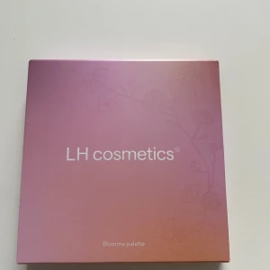 Blomma palett från LH Cosmetics - Blomma palett från LH Cosmetics med ett vackert blommigt tema. Paletten är vegansk och dermatologiskt testad, perfekt för att skapa olika ögonskuggslooker. Den har en elegant rosa förpackning med blommönster. Ny oöppnad