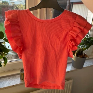 Korallfärgad topp från Zara - Säljer en superfin korallfärgad topp från Zara i storlek S. Toppen har volangdetaljer på ärmarna och är ribbad för en snygg look. Perfekt för vår och sommar! 🌸