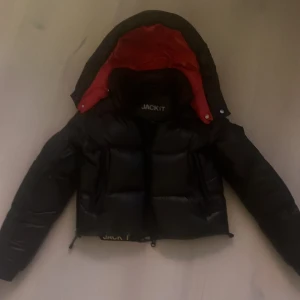 Svart och röd pufferjacka från JACK1T - Säljer en sprillansny assnygg svart pufferjacka från JACK1T med röd insida. Jackan är varm och lätt, perfekt för kalla dagar. Den har en dragkedja och är långärmad. Jackan är i mycket bra skick och har en modern design. Passar typ alla stiler.