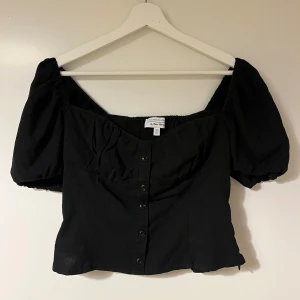 Svart blus från & Other Stories - Snygg svart blus från & Other Stories med puffiga kortärmar och knappar framtill. Den har en smickrande passform och elastisk rygg för extra komfort. 