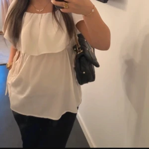Vit offshoulder blus - Säljer en stilren vit/krämvit offshoulder blus med volangdetaljer. Blusen har knytband i midjan för en justerbar passform och är perfekt för sommarens varma dagar💗💗