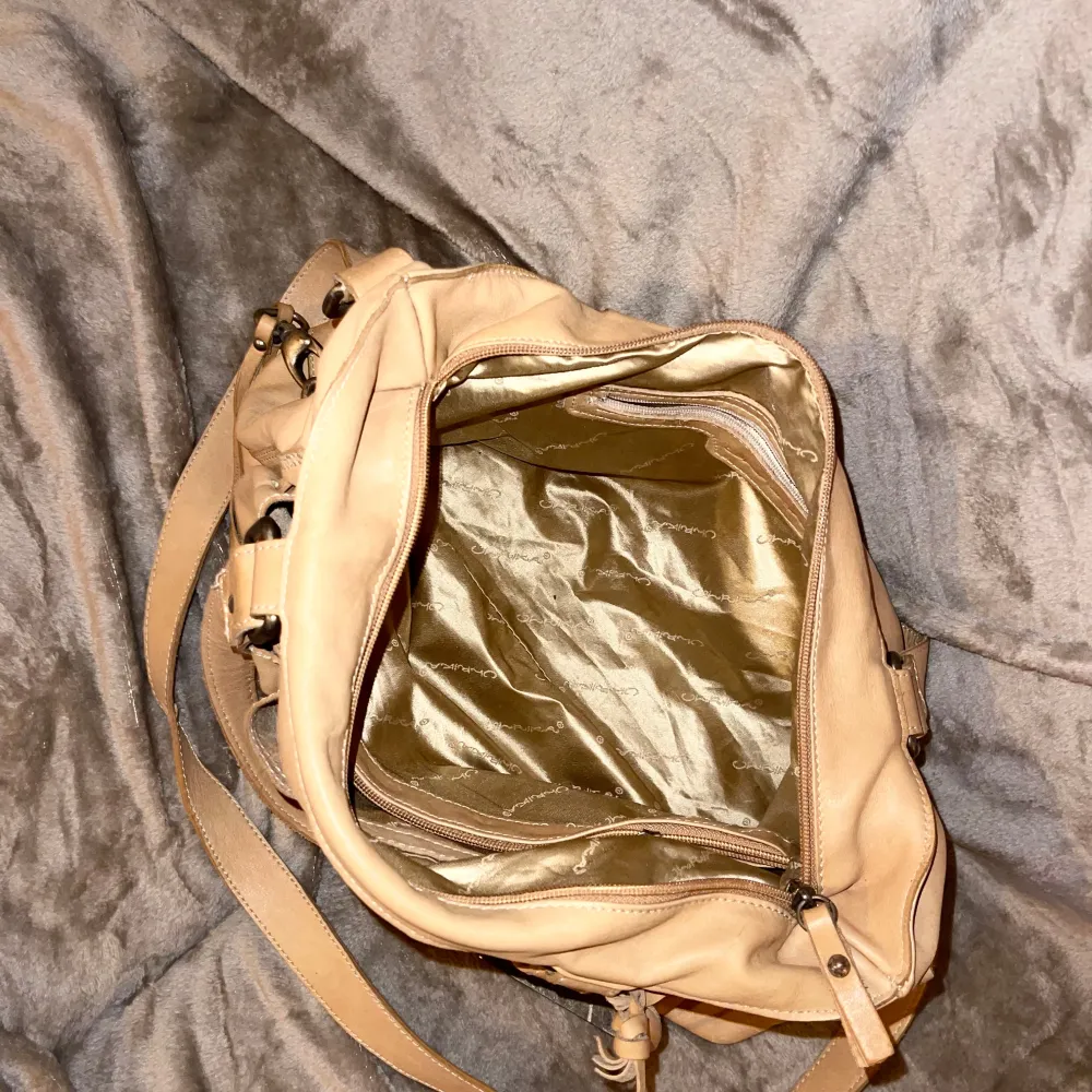 Säljer en snygg beige axelväska från Ulrika i skinn. Väskan har flera praktiska fack med dragkedja och en justerbar axelrem. Perfekt för vardagsbruk och rymmer allt du behöver. Den är i mycket bra skick och redo för nya äventyr! . Laukut & Käsilaukut.