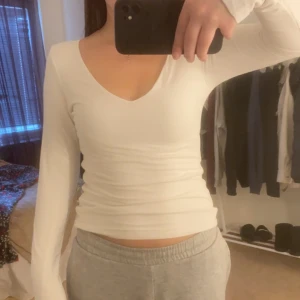 Vit långärmad topp - Säljer en superfin vit långärmad topp i mycket bra skick. Den har en v-ringad design och är perfekt för både vardag och fest. Materialet är mjukt och stretchigt, vilket gör den bekväm att bära hela dagen. Passar perfekt till jeans eller kjol!
