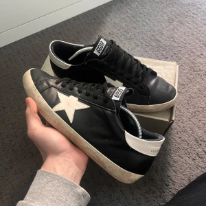 Golden Goose - Säljer ett par svarta Golden Goose i bra skick. Köpte skorna på NK i Stocholm i somaras, skorna är i jätte bra skick och inga fel med dom, fås med låda, kort, dustbag, köpte dessa helt nya för 5500kr, säljer dom för 1499 som jag tycker är ett extremt bra pris! Skriv om ni har frågor/ Theo 