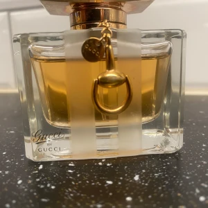 Gucci premiere Eau de Toilette - Säljer en elegant och lyxig parfymflaska från Gucci. Flaskan är i glas med en guldig kork och har en fin detalj i form av en liten guldring. Doften är en Eau de Toilette, perfekt för både vardag och fest. Flaskan rymmer 50 ml och är tillverkad i Frankrike.  Denna parfym har då också slutat att tillverkas vilket ger den ett nypris på ca 4000-5000kr