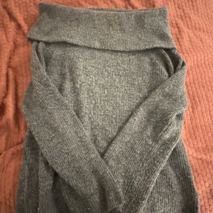 Grå stickad polotröja från H&M - Mysig grå stickad polotröja från H&M. Perfekt för kyliga dagar med sin mjuka och bekväma passform. Tröjan har långa ärmar och en bred polokrage som ger extra värme och stil.