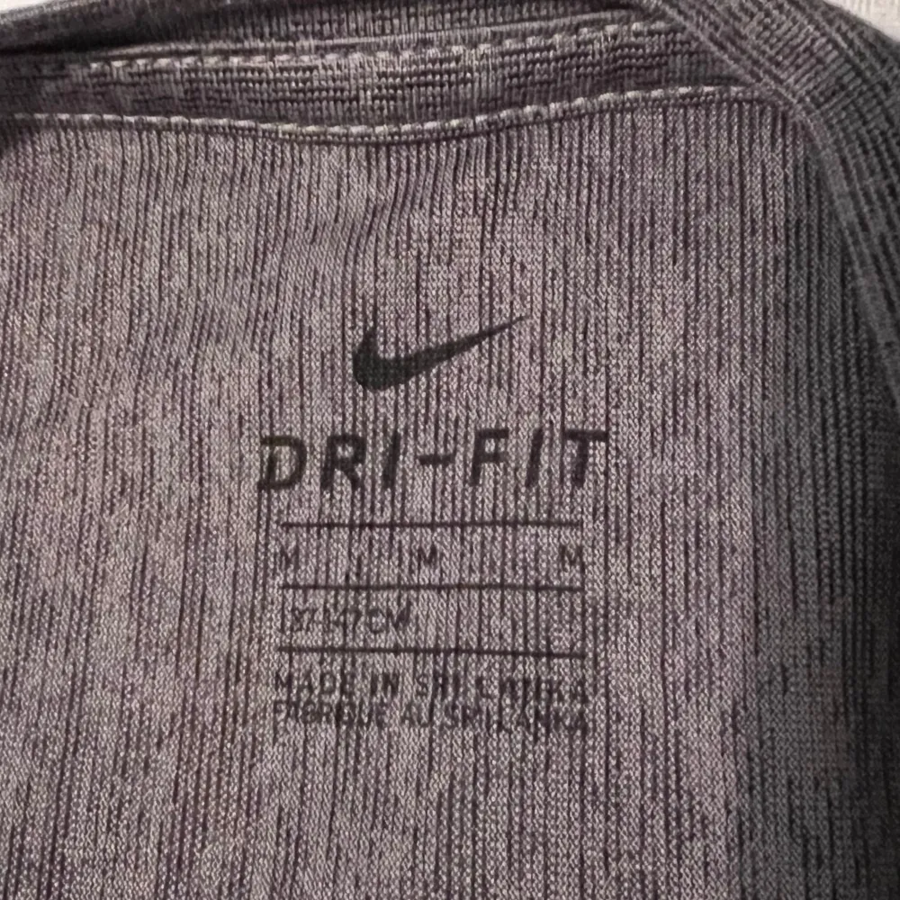 Säljer en grå Dri-FIT t-shirt från Nike i mycket bra skick. Perfekt för träning med sin fukttransporterande teknik. Den har en klassisk Nike-logga i vitt på bröstet och är kortärmad.. T-shirts.