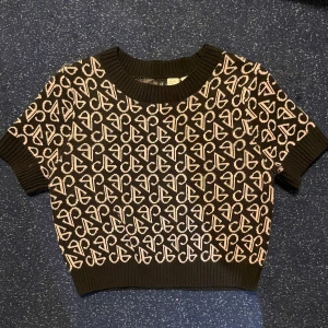 Blackpink X h&m top  - Snygg croppad topp i svart med rosa mönster. Den har korta ärmar och en ribbad kant vid halsen. Köpt vid släpp av BLACKPINK x HM collab för några år sedan. Knappt använd. Bekväm och mjuk :) originalpris 199kr