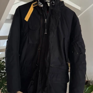 Svart vinterjacka från Parajumpers - Säljer en svart Parajumpers vinterjacka i slim fit. Den har en snygg pälsdetalj på huvan och flera praktiska fickor. Perfekt för kalla vinterdagar! 🖤