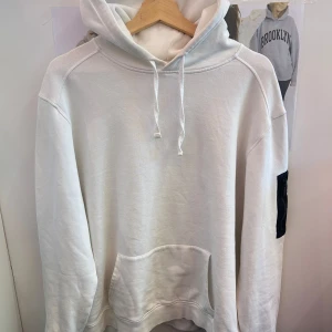 Vit hoodie från Snoot - Säljer en snygg vit hoodie från Snoot i storlek XL. Den har en klassisk design med en stor ficka fram och en cool svart detalj med dragkedja på ärmen. Perfekt för både höst och vår, och den är supermjuk och bekväm. Passar perfekt för alla. Jättefin skick utan några defekter. 