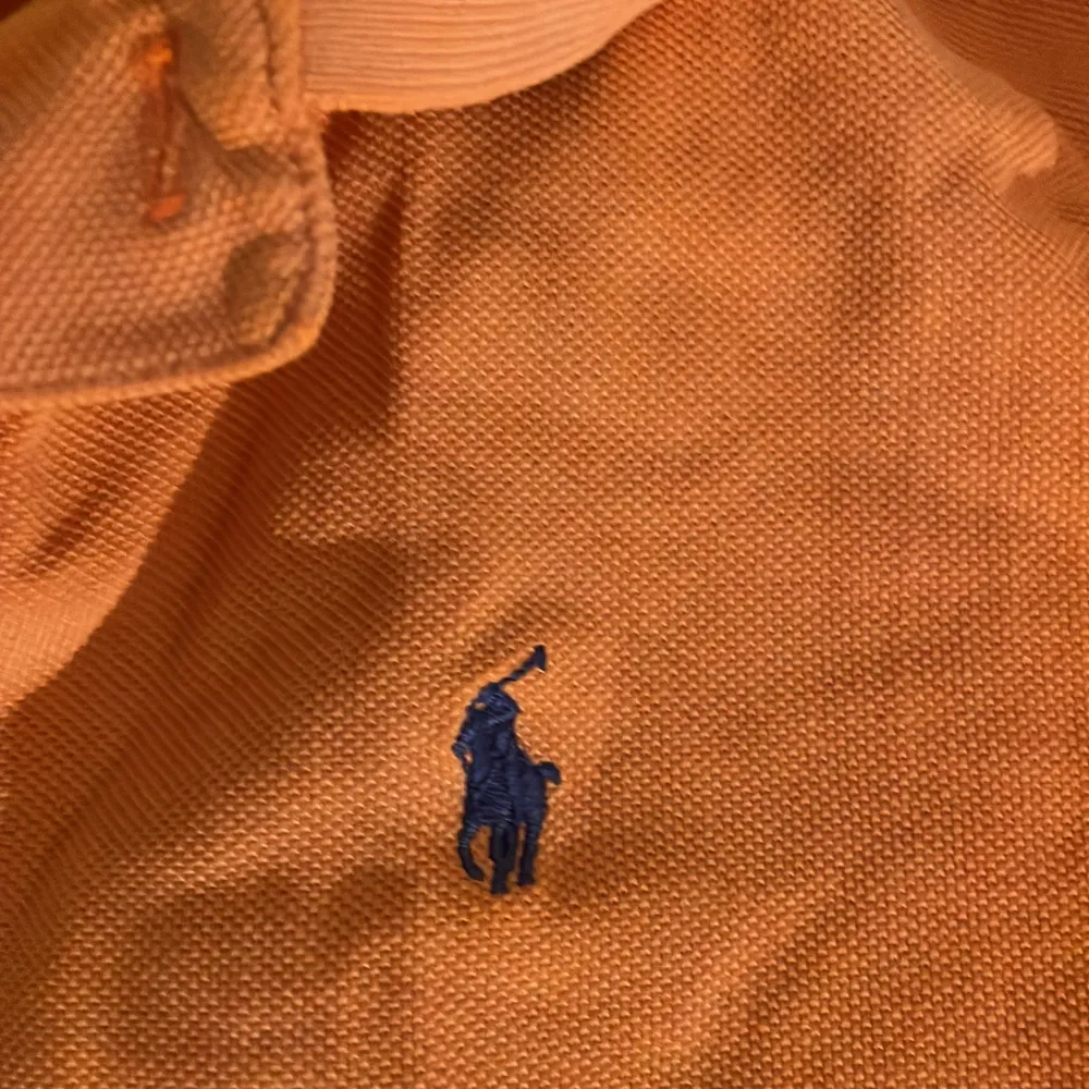 Säljer en snygg orange pikétröja från Polo Ralph Lauren i storlek M. Tröjan har korta ärmar och en klassisk krage med knappar. Den är broderad med det ikoniska Polo-loggan i blått på bröstet. Perfekt för en avslappnad men stilren look!. T-paidat.