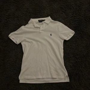 Vit slim fit pikétröja från Ralph Lauren i storlek s - Säljer en klassisk vit pikétröja från Ralph Lauren i slim fit. Tröjan har korta ärmar och en broderad logotyp på. Den är storlek s och använd 3 gånger efter att jag köpte den