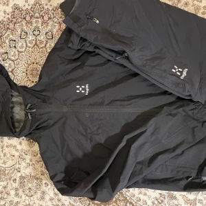 Svart vindjacka från Haglöfs - Säljer en svart vindjacka från Haglöfs med dragkedja och huva. Kommer med byxor till. Pris kan diskuteras 