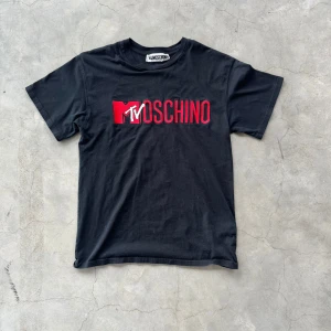 Svart t-shirt från Moschino - Snygg svart t-shirt från Moschino med röd och vit text🔥🔥Den är i mycket bra skick! Inga defekter förekommer!🤩 Storleken på denna t-shirt är XS!🎉 Kontakta mig vid minsta fundering!🤩                          ⚠️VID SNABBAFFÄR KAN PRISET DISKUTERAS⚠️