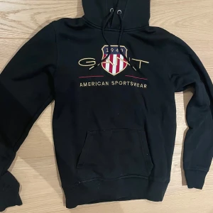 Svart Gant hoodie - Har inte använts pả väldigt länga och därför säljer jag den. Den är i väldigt bra skick utan nägra tydliga defekter eller skavanker. Storlek: S Normal i passformen