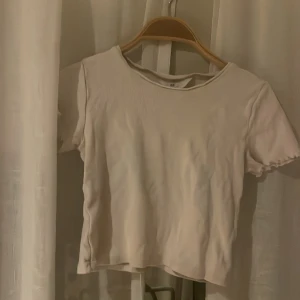Vit kortärmad topp från H&M - Säljer en enkel och stilren vit topp från H&M. Den har korta ärmar och en rund halsringning. Perfekt för en avslappnad look.