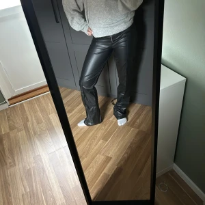 Svarta skinnbyxor - Snygga svarta skinnbyxor med låg midja och bootcut-stil. Byxorna har en dragkedja framtill och ger en cool look. Perfekta för att lyfta vilken outfit som helst. Aldrig använda.