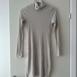Beige ribbad klänning - Säljer en stilren beige ribbad klänning med polokrage och långa ärmar. 