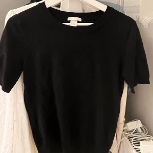Svart kortärmad topp - Säljer en stilren svart kortärmad topp i mjukt material. Perfekt för en enkel och snygg look. Toppen har en tight passform och rund halsringning.