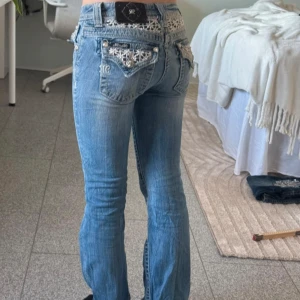 Miss Me bootcut jeans - ‼️Jeansen är just nu reserverade så går ej att köpa‼️                                                                              Snygga blå jeans från Miss Me med unika spetsdetaljer på bakfickorna och över linningen. Jeansen är i storlek 14 och passar storlek W23/24. De har en låg midja och en bootcut-stil som ger en avslappnad look. De har en mindre fläck som går att se på sista bilden. Det finns fler bilder som visar detaljer och mått bättre så tveka inte att fråga om du är intresserad💕