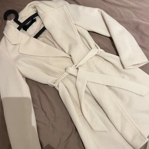 Beige kappa från Vero Moda, S - Vårig kappa från Vero Moda med knytband i midjan. Perfekt för våren. Beige, mycket bra skick!! Storlek S.